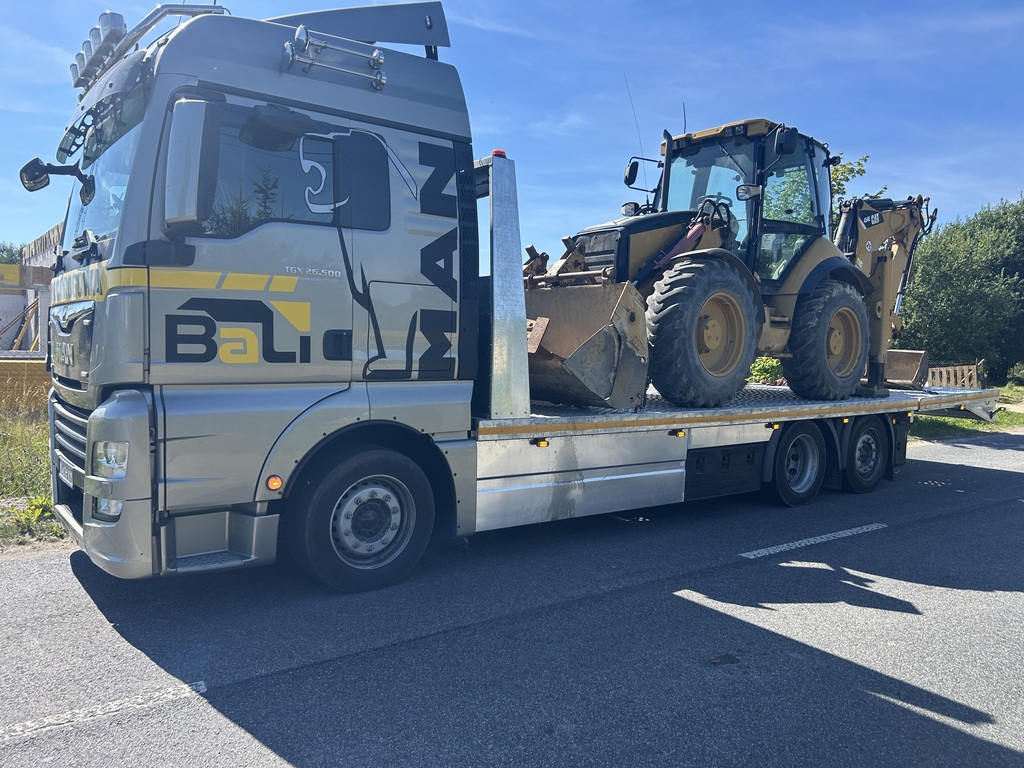 Transport maszyny rolniczej na samochodzie niskopodwoziowym w Koszalinie.